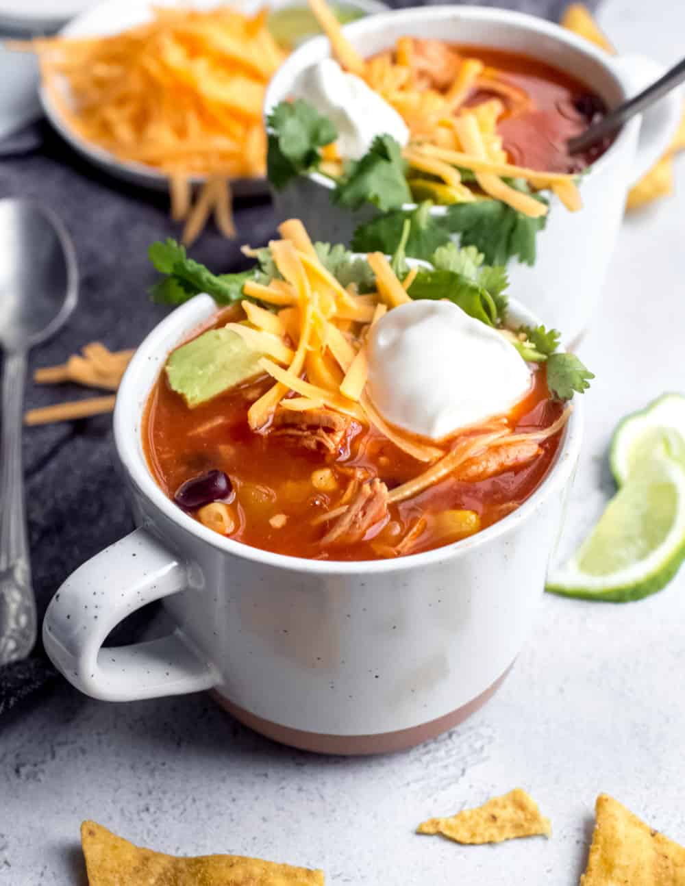 Sopa de tortilla en una taza blanca, cubierta con queso y crema agria