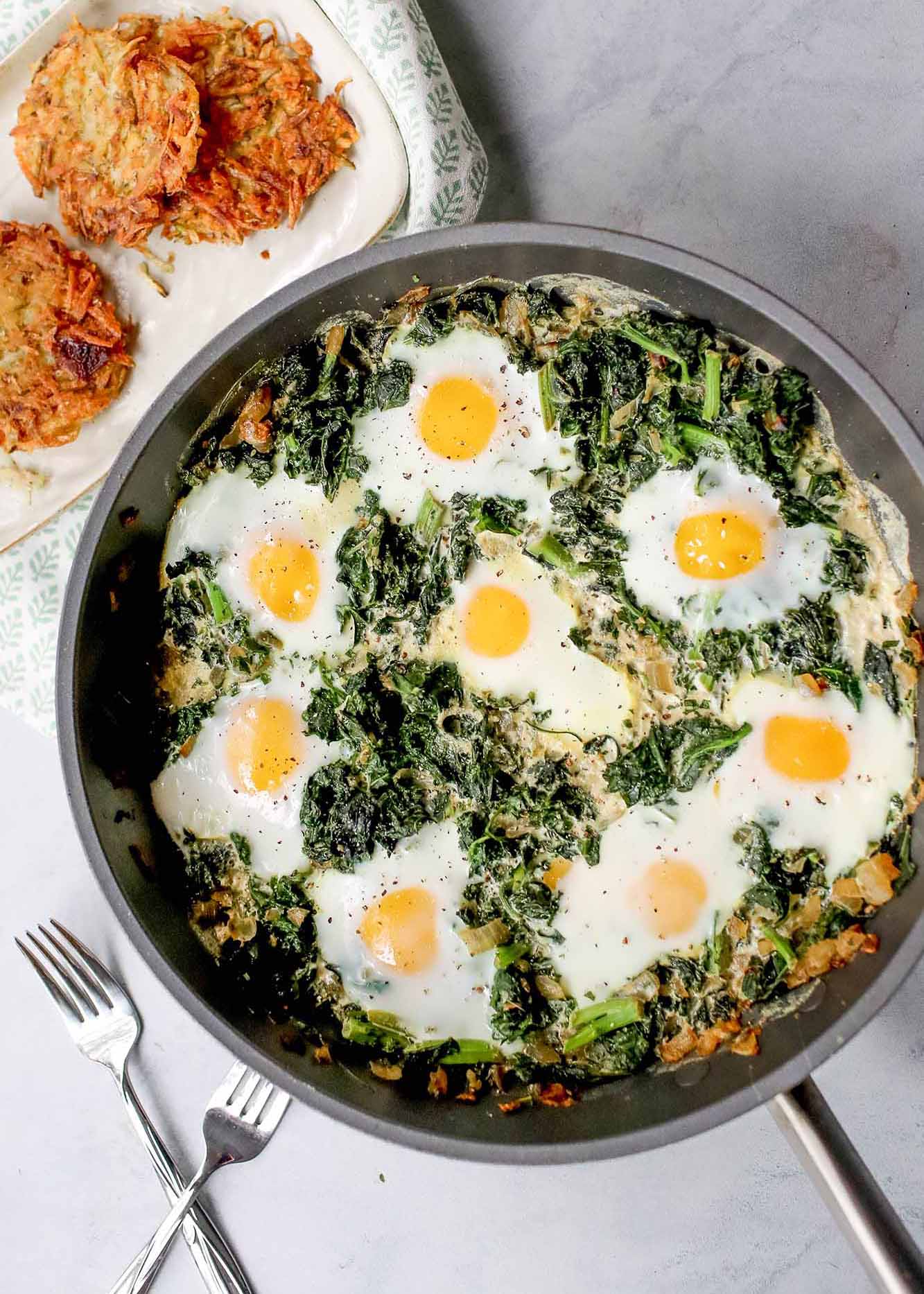 Green Shakshuka in a skillet with crispy latkes alongside