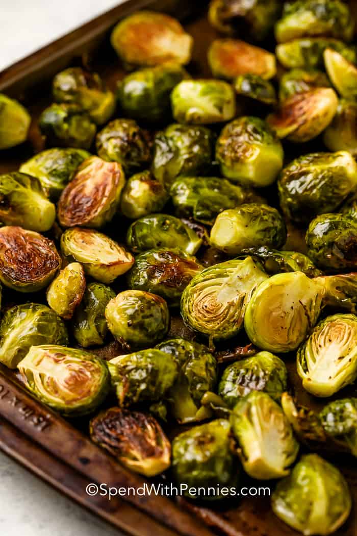 Baked, halved brussel sprouts, oiled and seasoned with pepper in a baking tray