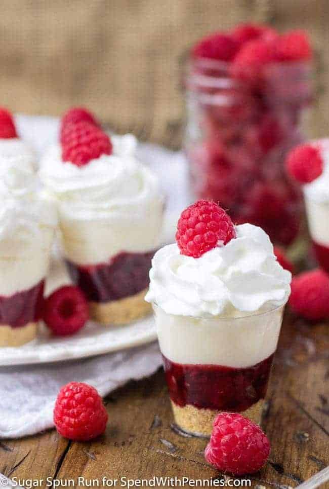 Raspberry Cheesecake Dessert Shooters with jar of raspberries in the background