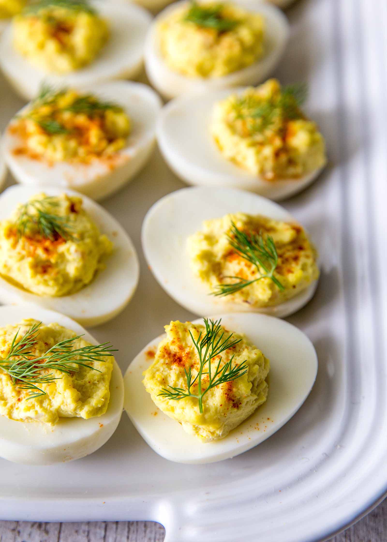 Perfect Deviled Eggs with Dill - - Close up of deviled eggs with dill and paprika on a white platter