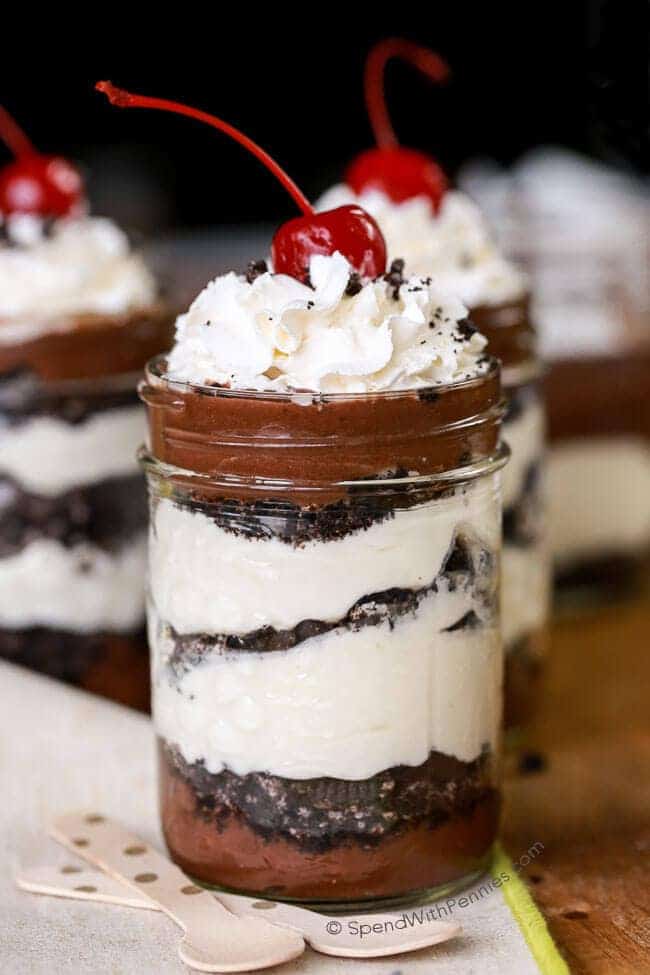 Oreo Chocolate Cheesecake Parfait ve skleněném hrnečku se šlehačkou a třešničkou nahoře