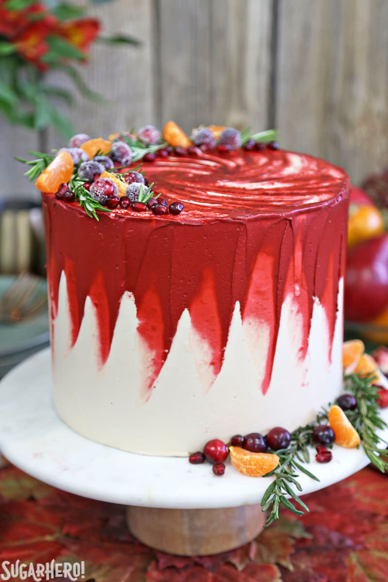 Brown Sugar Cranberry Cake - en soporte de pastel de mármol decorado con fruta fresca y romero | De SugarHero.com