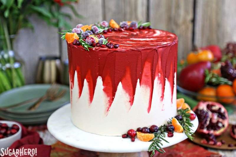 Brown Sugar Cranberry Cake - en soporte de pastel de mármol decorado con fruta fresca y romero | De SugarHero.com