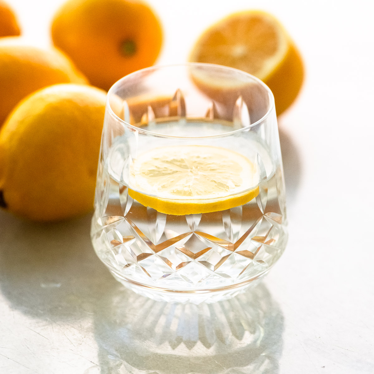 Un vaso de agua de limón con limones enteros.