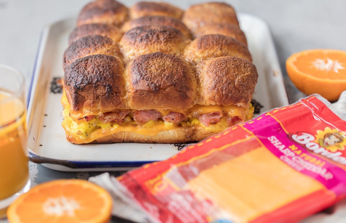 Sandwiches de jamón, huevo y queso en una bandeja para hornear junto a un paquete de lonchas de queso