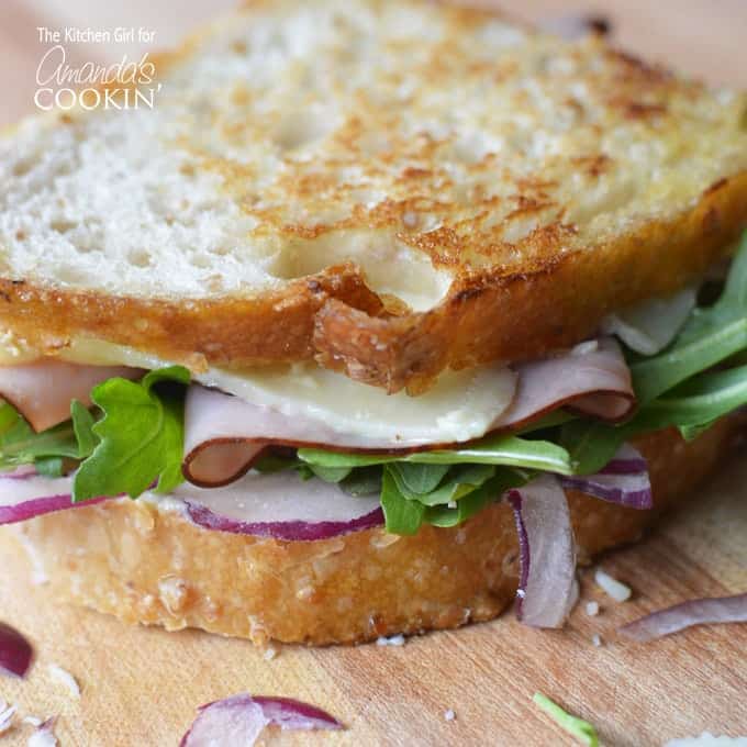 Sandwich de queso cheddar tostado, jamón y rúcula