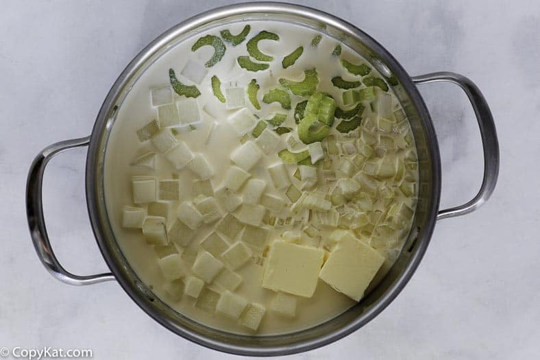 Cocción de sopa de papa, tiene mantequilla, apio, papas y más en una olla grande.