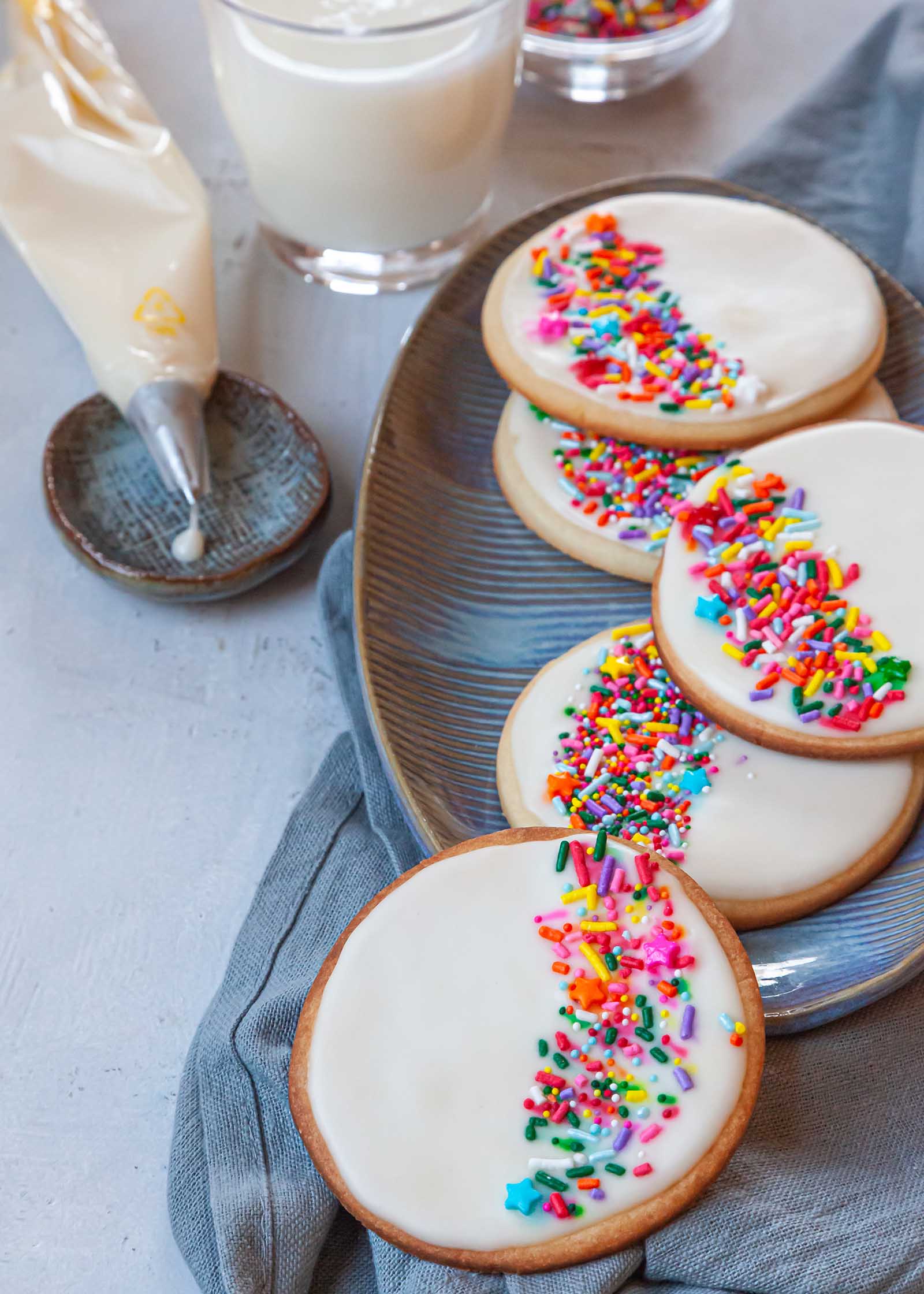 Easy Royal Icing Recipe decorates a platter of circle cookies topped with sprinkles.
