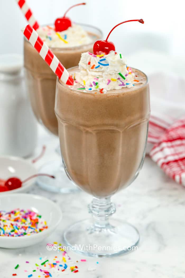 Chocolate milkshakes in glasses with whipped cream cherries and sprinkles on top