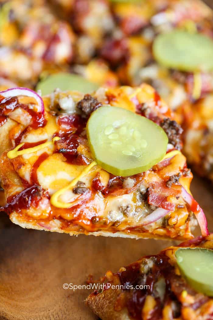 una rebanada de pizza de hamburguesa con queso cubierta con pepinillos