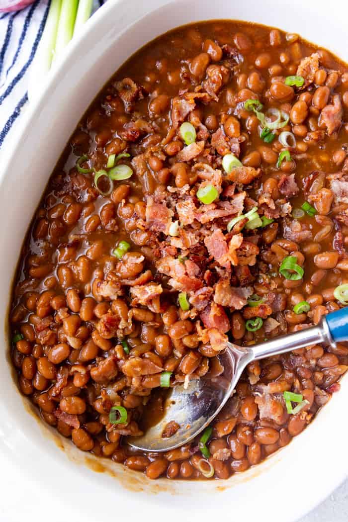Baked Beans with a spoon garnished with green onions and bacon