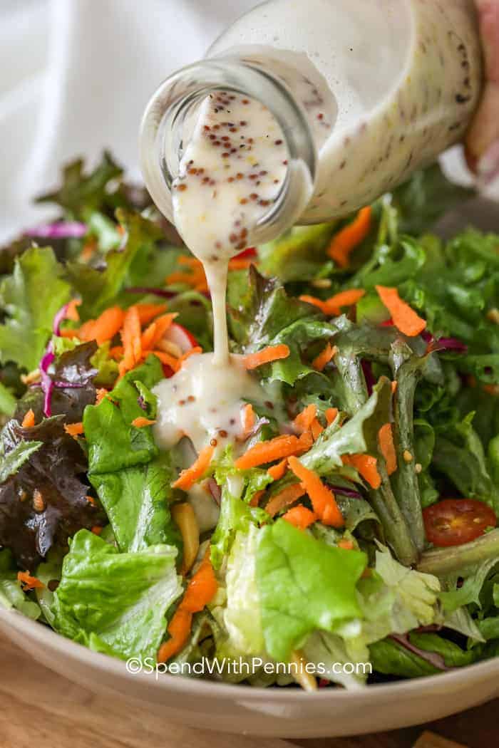 Pouring honey mustard dressing over a salad