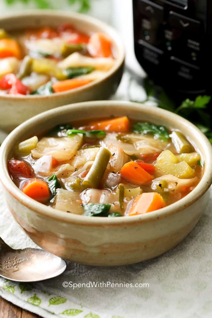 Sopa de repollo y verduras en olla de cocción lenta en tazones