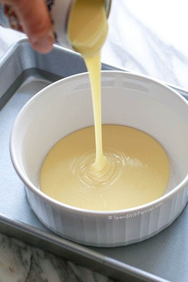 Verter la leche condensada en una fuente para hornear blanca