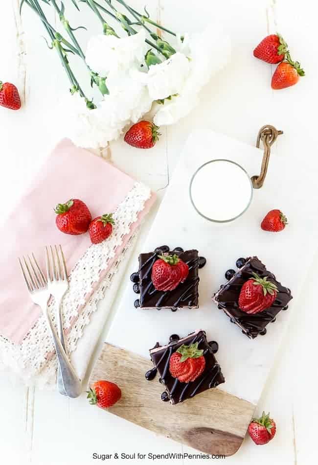 Brownies de capa de fresa sobre una placa de mármol con servilletas y bayas en el fondo