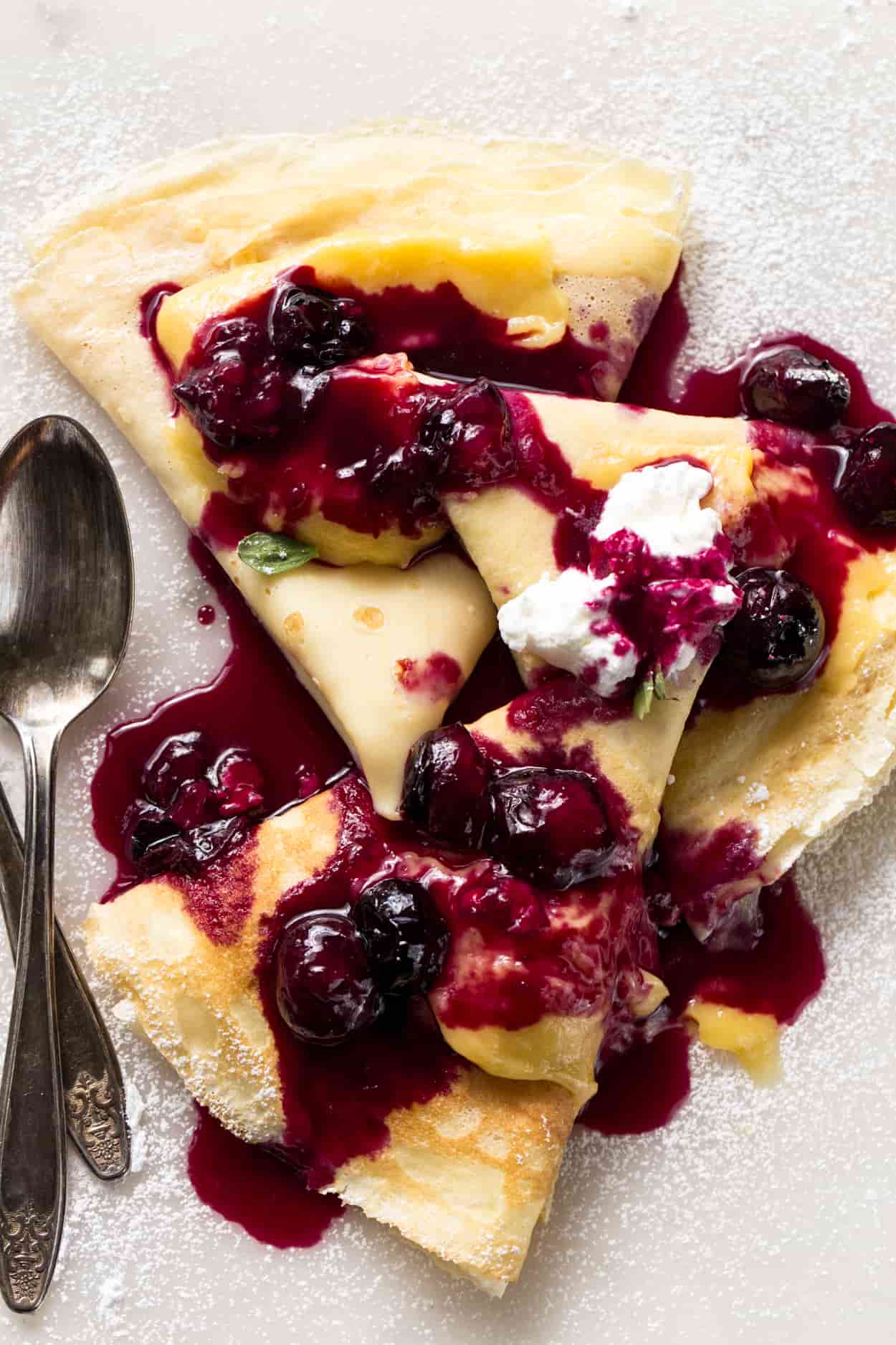 Crepes recipe with custard filling, whipped cream, and blueberry sauce. The best crepe recipe!