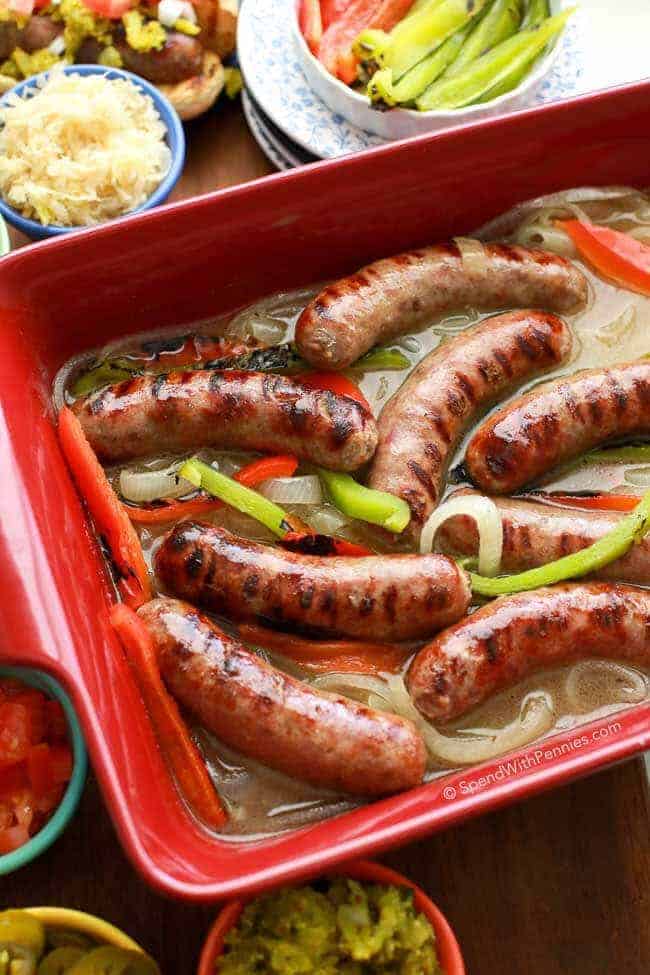 Overhead shot of red pan full of brats, peppers and onions