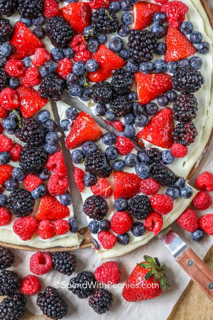 Overhead shot of fruit pizza, removing a slice