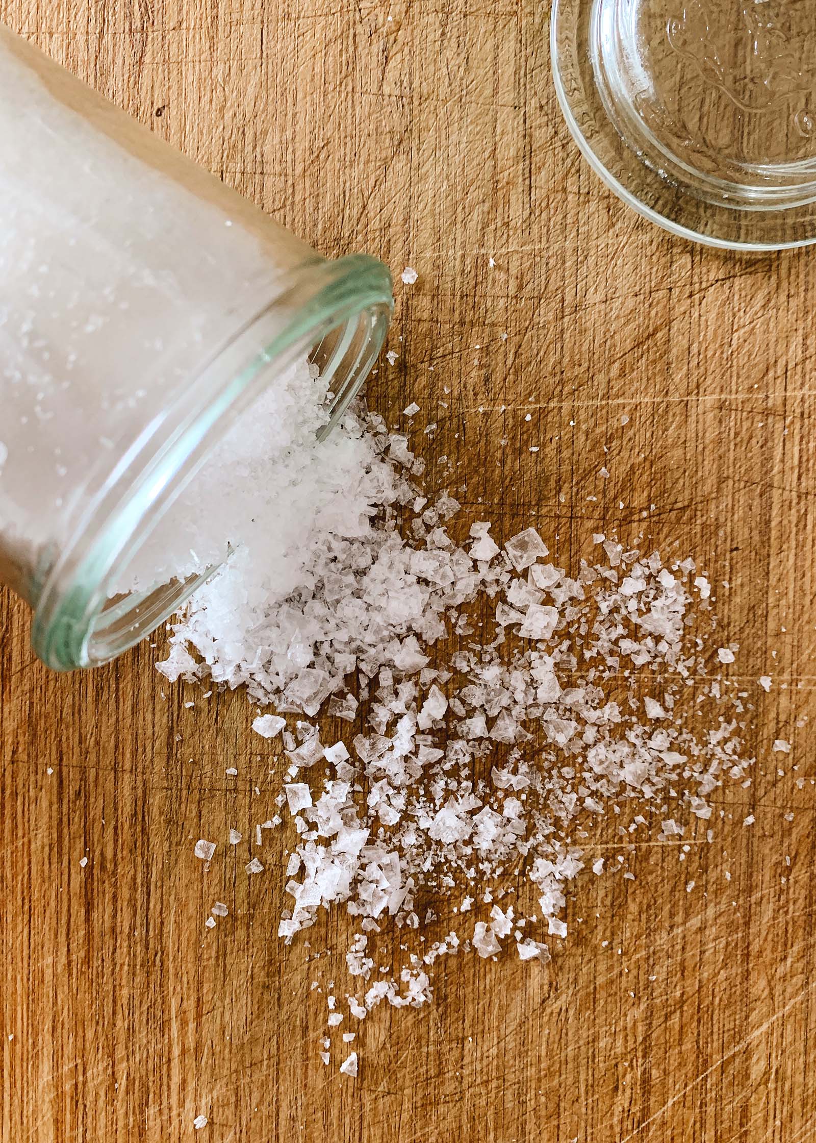 What are sea salt flakes? Maldon sea salt spilled from a jar on a counter.