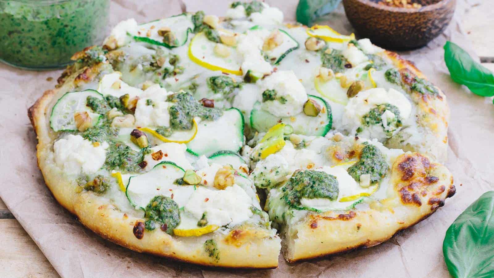 White pesto pizza with zucchini on a wooden surface.