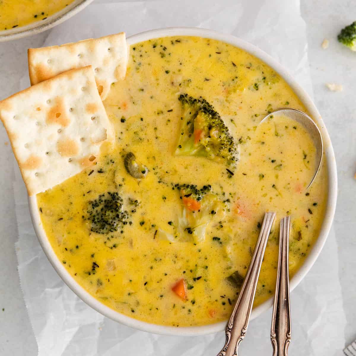 Broccoli potato soup in a bowl with crackers on the side.